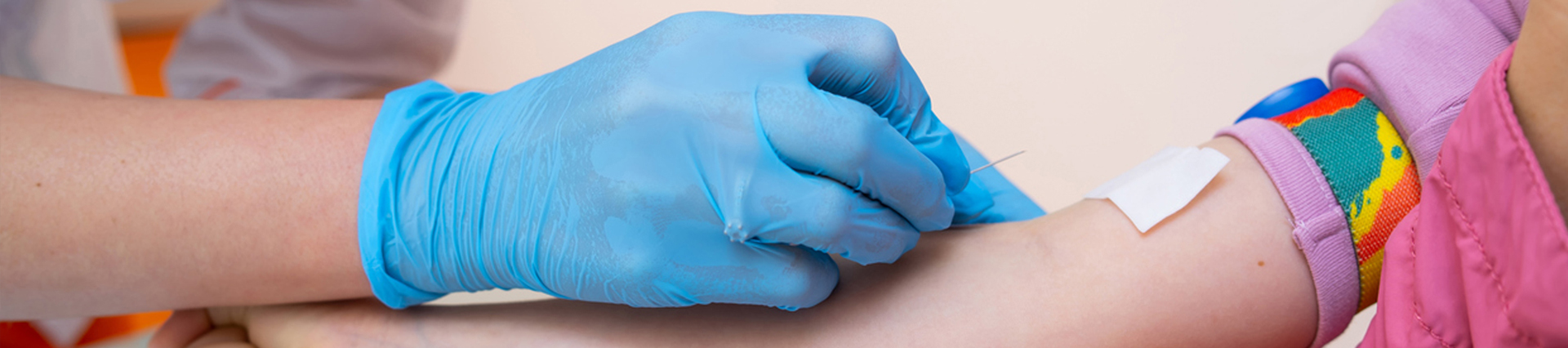 Gloved hand drawing blood from a child's arm